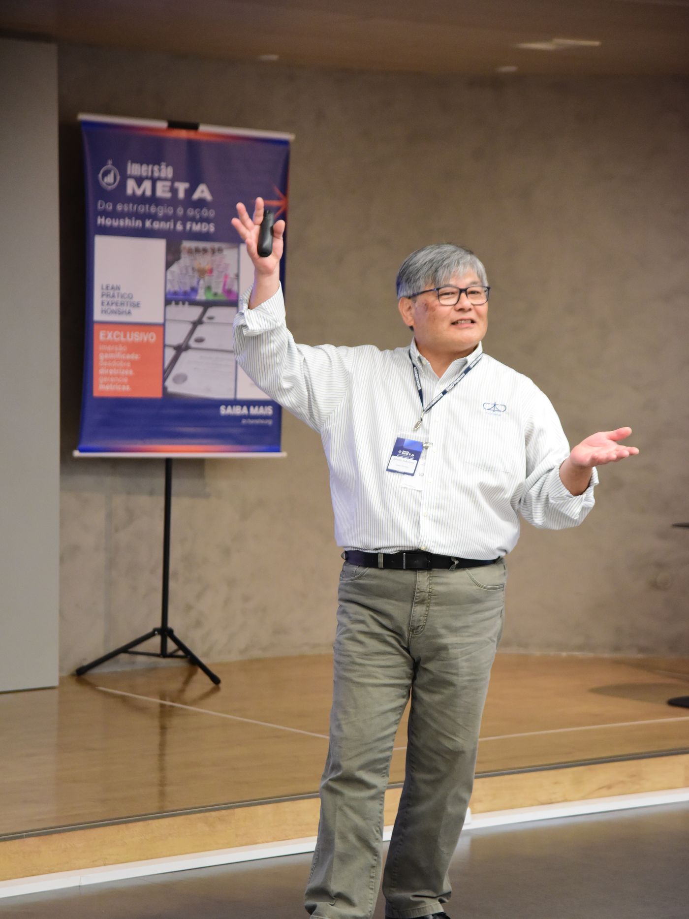 Alberto Nakamura apresentando de pé, com os braços abertos, durante a Imersão META de Hoshin Kanri